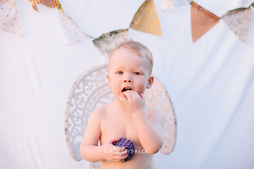 Boy sitting in front of sheets hung from clothesline