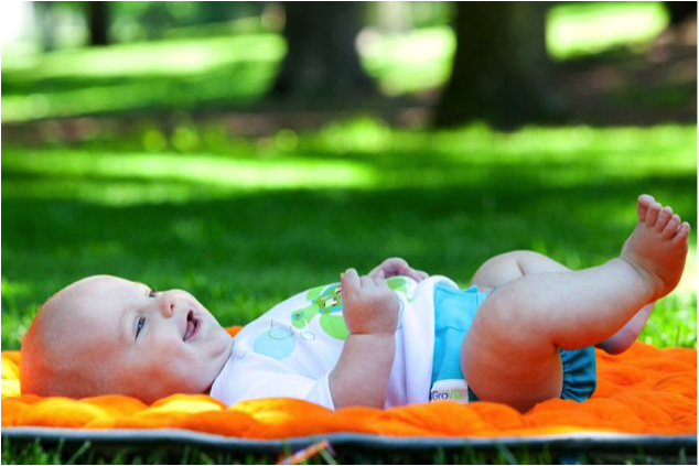 Baby in MCN lying on blanket on grass